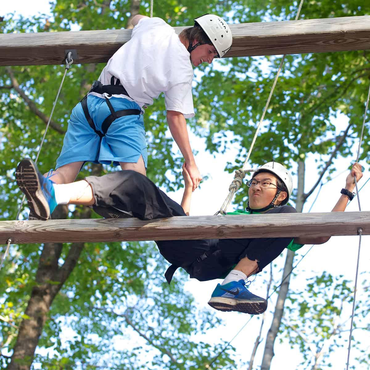 students climb the outdoor challenge course